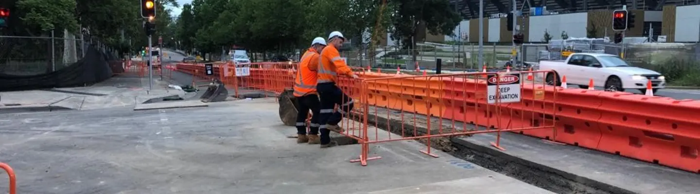 Safety barriers and fencing installed along a light rail track to protect pedestrians and secure the construction area.