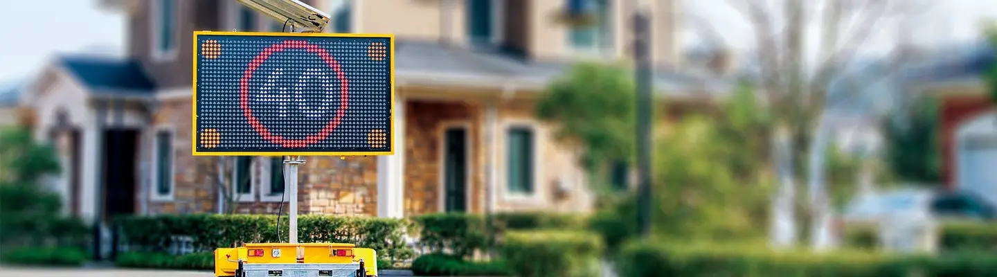 An electronic message board sign on the roadside displaying safety or construction information near a work zone with barriers.