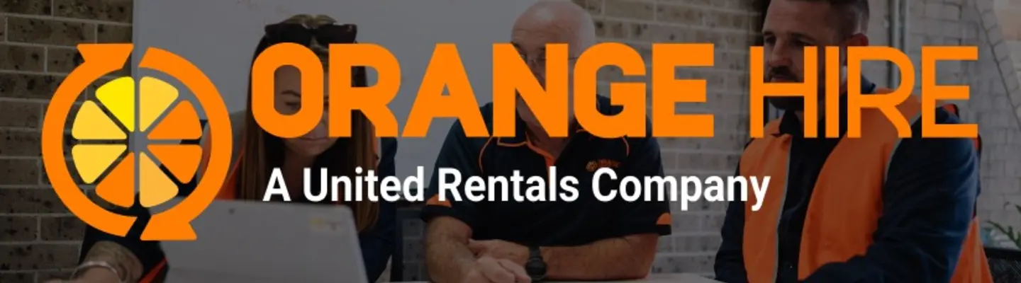 Men in an office discussing construction plans, with safety diagrams and equipment layouts visible on screens or papers.