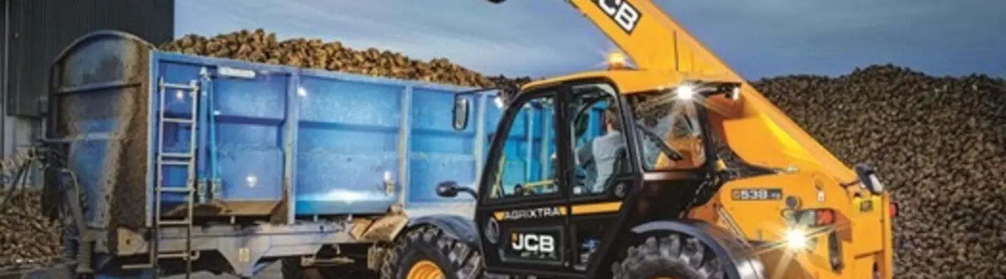 Man operating a telehandler on a construction site near safety barriers, lifting materials for site development.