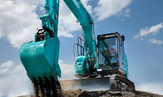 A man operating heavy equipment to dig and move sand at a construction site, focusing on earthmoving tasks.