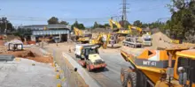 Construction workers using machinery, tools, and safety barriers on an active site to ensure efficient and safe operations.