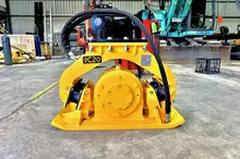 Plate compactor machine on a construction site near safety barriers, used for compacting soil and maintaining ground stability.