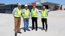 Group of workers standing in front of a newly completed office building with safety barriers in place.